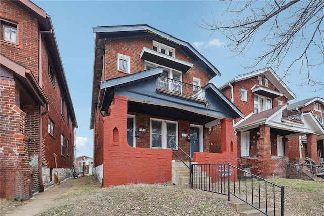 view of front facade featuring brick siding and a balcony