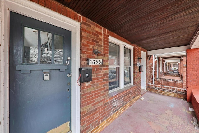 property entrance featuring a porch and brick siding