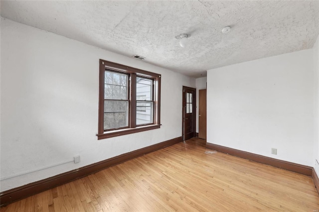 unfurnished room featuring baseboards, a textured ceiling, and light wood finished floors