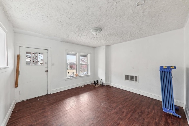 spare room featuring wood finished floors, a textured ceiling, and baseboards
