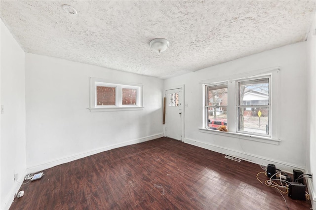spare room featuring dark wood-style floors, a textured ceiling, and baseboards