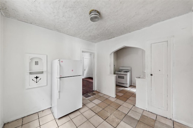 kitchen with white appliances, arched walkways, and light tile patterned floors
