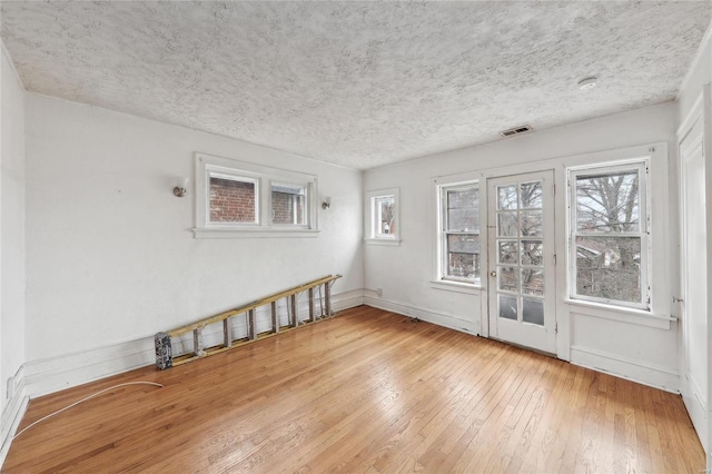 spare room with hardwood / wood-style floors, baseboards, and a textured ceiling