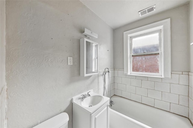 bathroom with toilet, a bath, and vanity