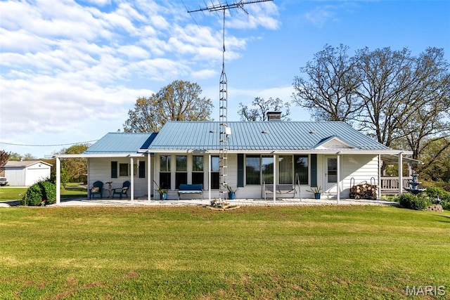 rear view of house with a lawn, a patio area, metal roof, and a chimney