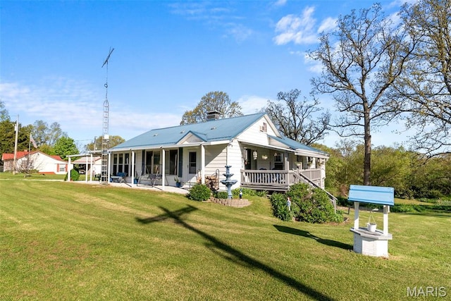 rear view of house featuring a yard, covered porch, metal roof, and a patio
