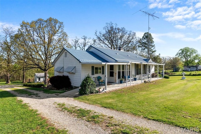 rear view of property with a yard, driveway, and metal roof