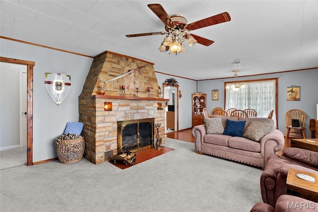 living room featuring ornamental molding, a ceiling fan, carpet flooring, and a fireplace