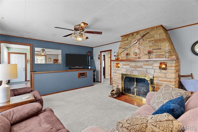 carpeted living area with ceiling fan, crown molding, and a fireplace