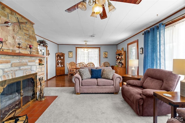 carpeted living room with a ceiling fan, ornamental molding, and a stone fireplace