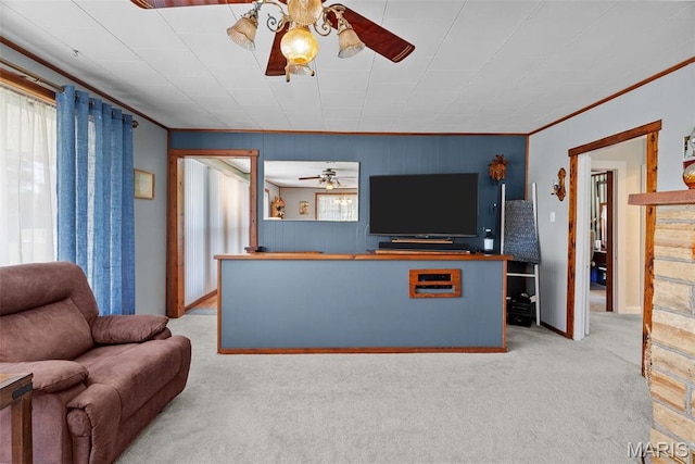 living area featuring ceiling fan, carpet, crown molding, and baseboards