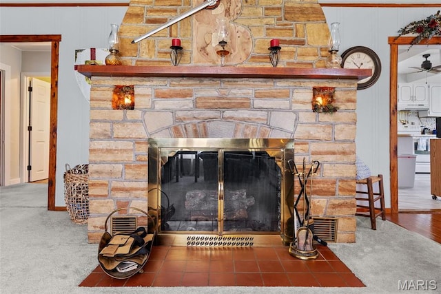 detailed view of a stone fireplace, under cabinet range hood, white range with electric cooktop, and ceiling fan