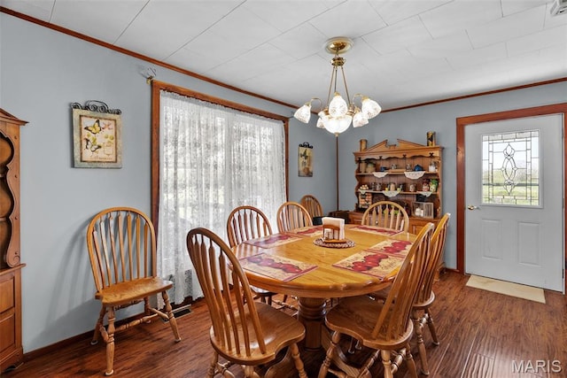 dining space featuring healthy amount of natural light, ornamental molding, dark wood finished floors, a chandelier, and baseboards