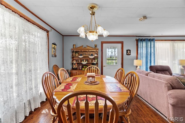 dining area with wood finished floors, a chandelier, and ornamental molding