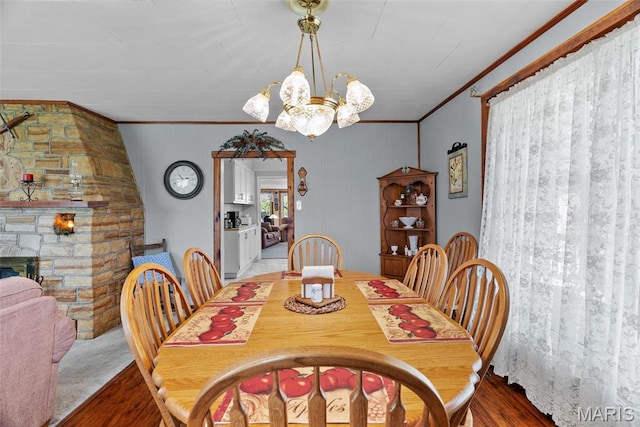 dining space with ornamental molding, wood finished floors, a chandelier, and a fireplace