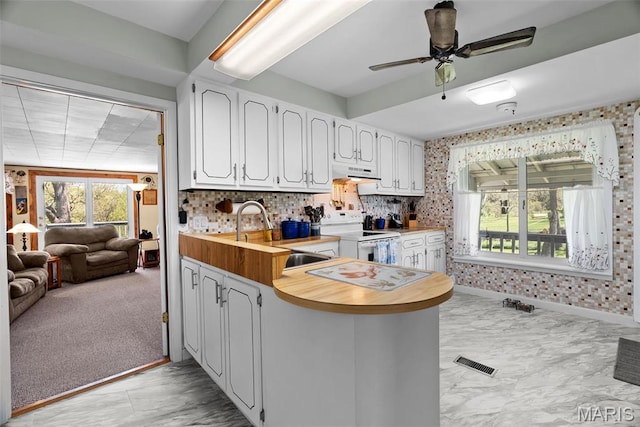 kitchen with white range with electric stovetop, a sink, range hood, a peninsula, and white cabinetry