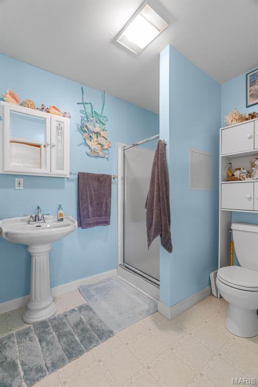 bathroom featuring a shower stall, baseboards, and toilet