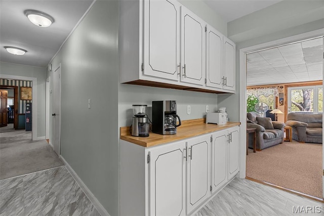 bar area with baseboards, light carpet, and light marble finish flooring