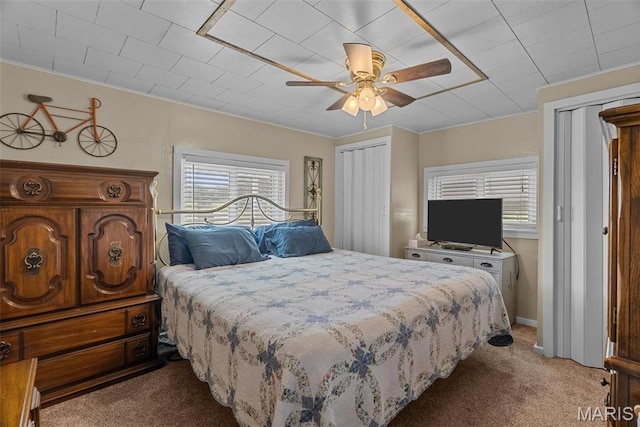 carpeted bedroom with multiple windows, multiple closets, a ceiling fan, and crown molding