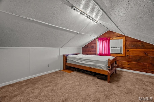 bedroom featuring a textured ceiling, vaulted ceiling, wood walls, baseboards, and carpet flooring