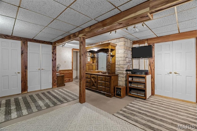 bedroom featuring carpet, a drop ceiling, wooden walls, and wainscoting
