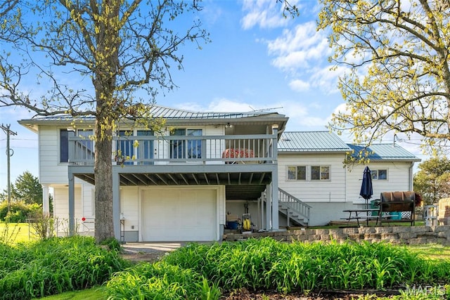 back of house with stairway, a garage, metal roof, and a deck