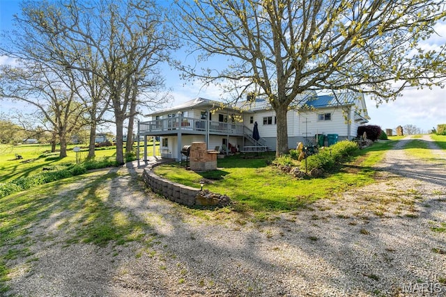 view of home's exterior with dirt driveway, a wooden deck, stairs, and a yard