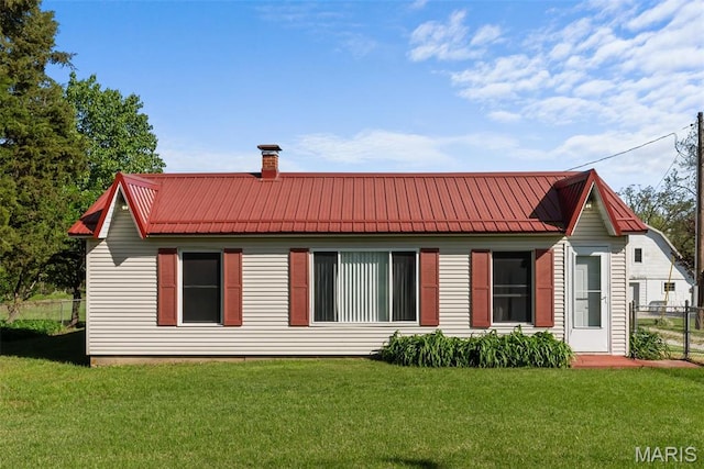 rear view of house featuring a chimney and metal roof