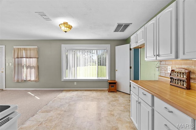 kitchen featuring baseboards, light countertops, white cabinets, and tasteful backsplash