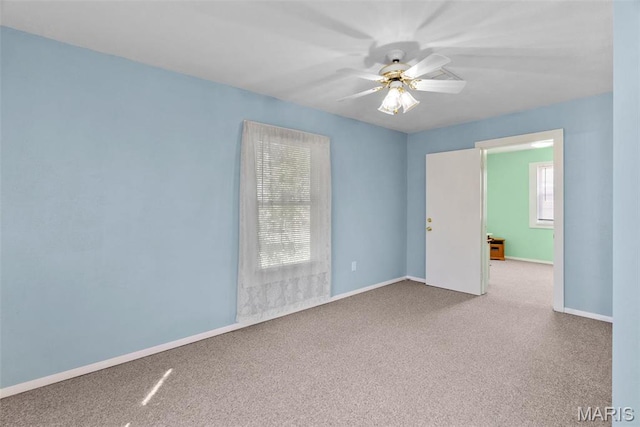 carpeted spare room featuring a ceiling fan and baseboards