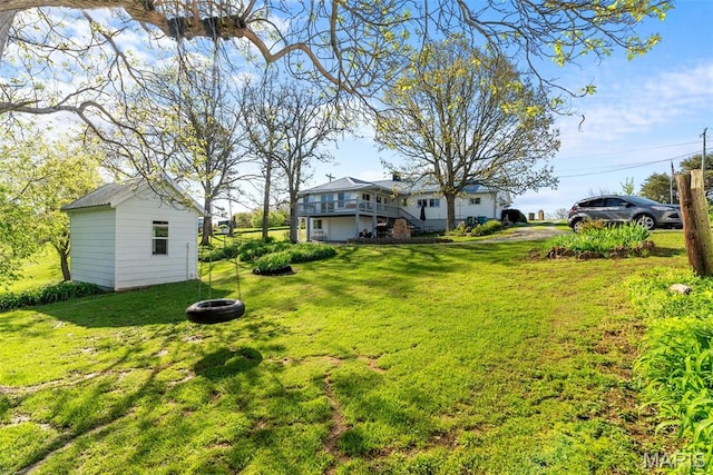 view of green lawn featuring a fire pit, an outbuilding, and a wooden deck