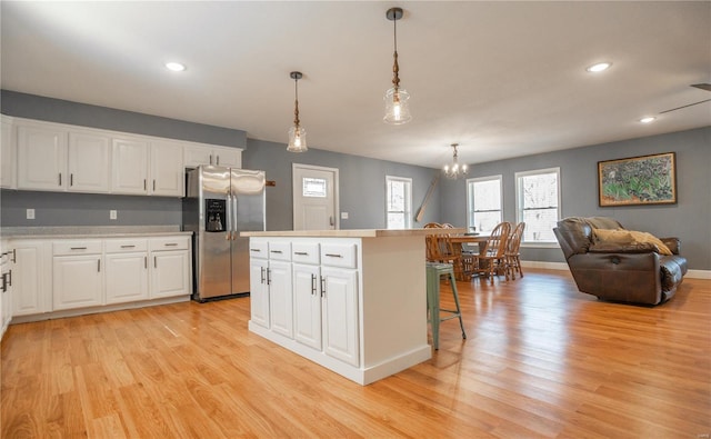 601 Broadway St, Van Buren, MO 63965 - kitchen with stainless steel fridge, light wood finished floors, a chandelier, a center island, and white cabinetry