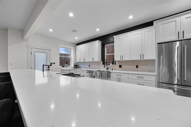 5818 Westminster Pl, Saint Louis, MO 63112 - kitchen with a sink, stainless steel appliances, white cabinetry, decorative backsplash, and recessed lighting