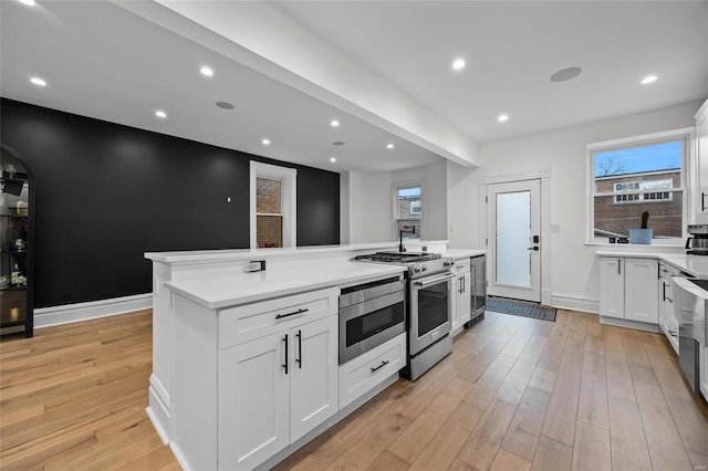 5818 Westminster Pl, Saint Louis, MO 63112 - kitchen with stainless steel appliances, beverage cooler, white cabinets, a center island, and recessed lighting