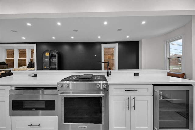 5818 Westminster Pl, Saint Louis, MO 63112 - kitchen with beverage cooler, stainless steel range, white cabinets, light countertops, and recessed lighting