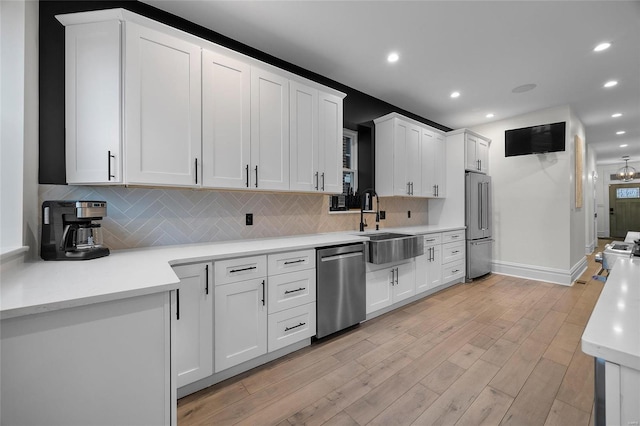5818 Westminster Pl, Saint Louis, MO 63112 - kitchen featuring stainless steel appliances, a sink, light wood-style floors, decorative backsplash, and light countertops