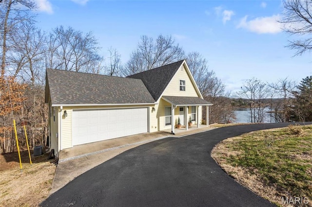 1451 Bella Vista Dr, Jackson, MO 63755 - view of front of house with covered porch, asphalt driveway, central air condition unit, a garage, and a shingled roof