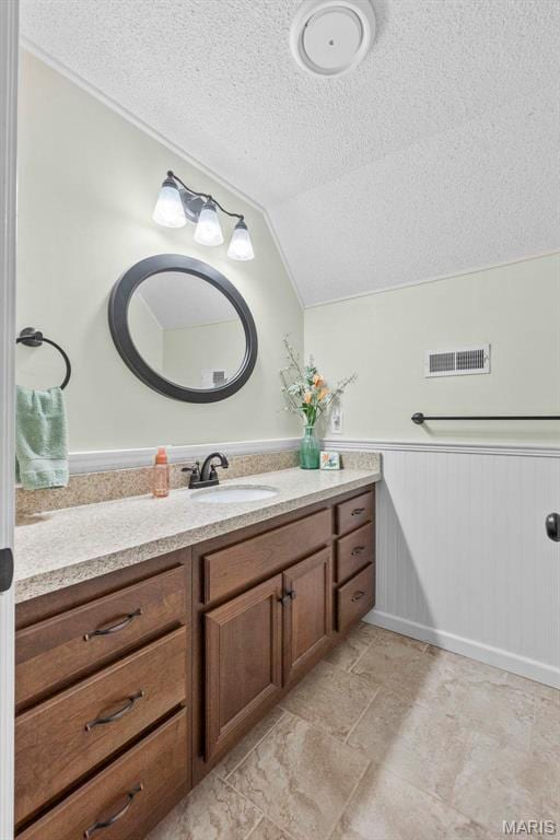 1451 Bella Vista Dr, Jackson, MO 63755 - bathroom with a textured ceiling, lofted ceiling, vanity, and a wainscoted wall