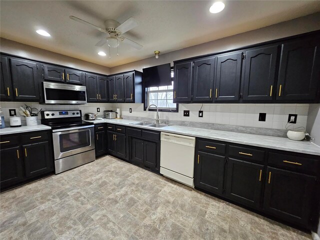 19782 Sugar Ln, Waynesville, MO 65583 - kitchen with stainless steel appliances, a sink, dark cabinets, a ceiling fan, and backsplash