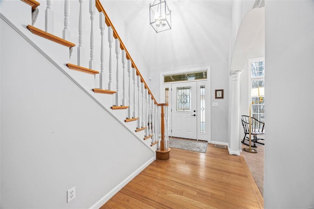 entryway featuring baseboards, hardwood / wood-style floors, a towering ceiling, and stairway