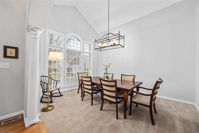 dining space featuring ornate columns, vaulted ceiling, light colored carpet, baseboards, and a chandelier