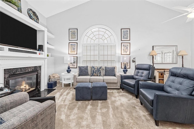 living room featuring carpet floors, a ceiling fan, a premium fireplace, and high vaulted ceiling