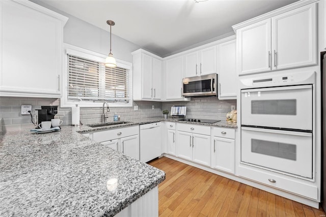 kitchen featuring white appliances, a sink, white cabinetry, pendant lighting, and decorative backsplash