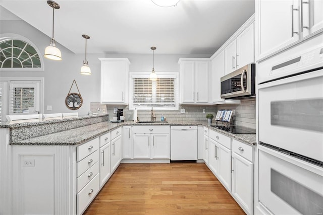 kitchen featuring white appliances, a sink, a peninsula, and white cabinetry