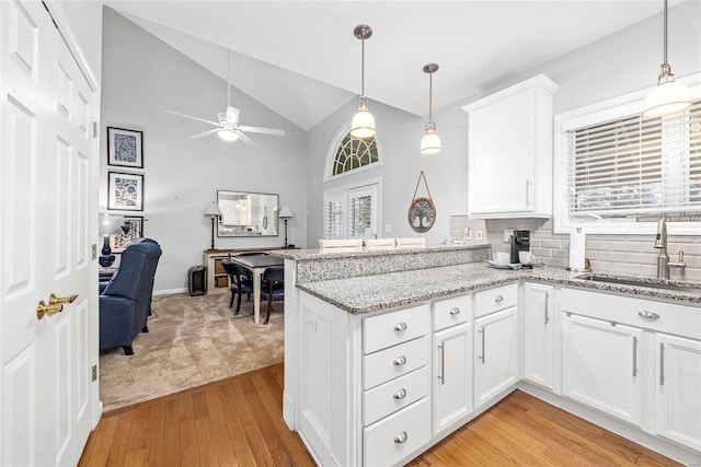 kitchen featuring a sink, light wood-type flooring, high vaulted ceiling, a peninsula, and a ceiling fan