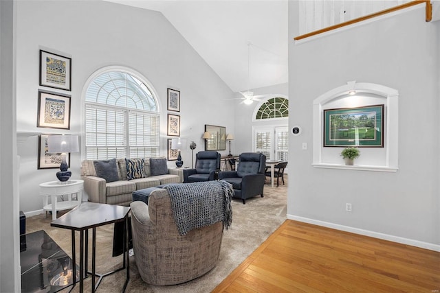 living room featuring high vaulted ceiling, wood finished floors, ceiling fan, healthy amount of natural light, and baseboards