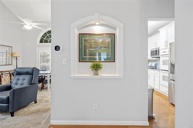 hall with light wood-style flooring and baseboards