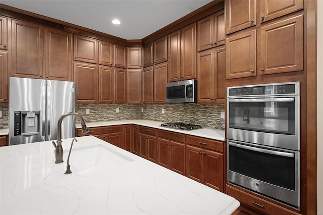 4036 Hempstead St, Saint Charles, MO 63301 - kitchen featuring stainless steel appliances, a sink, backsplash, light stone countertops, and brown cabinetry