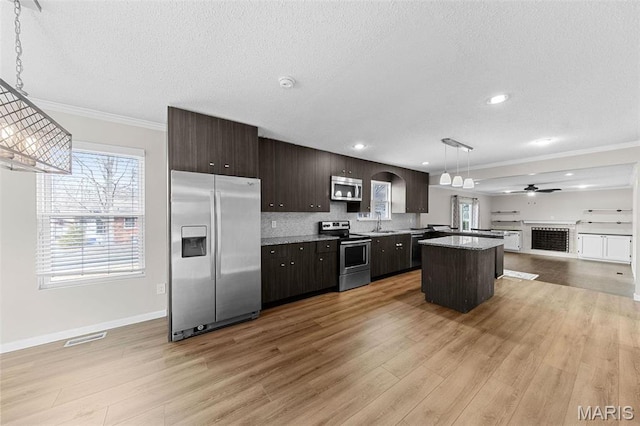 655 Lakewood Dr, Lake St Louis, MO 63367 - kitchen with appliances with stainless steel finishes, open floor plan, a textured ceiling, light wood-type flooring, and a kitchen island