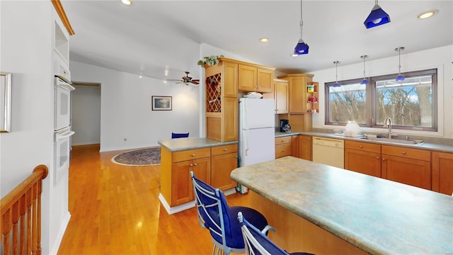 kitchen with a sink, white appliances, hanging light fixtures, light wood-style flooring, and recessed lighting